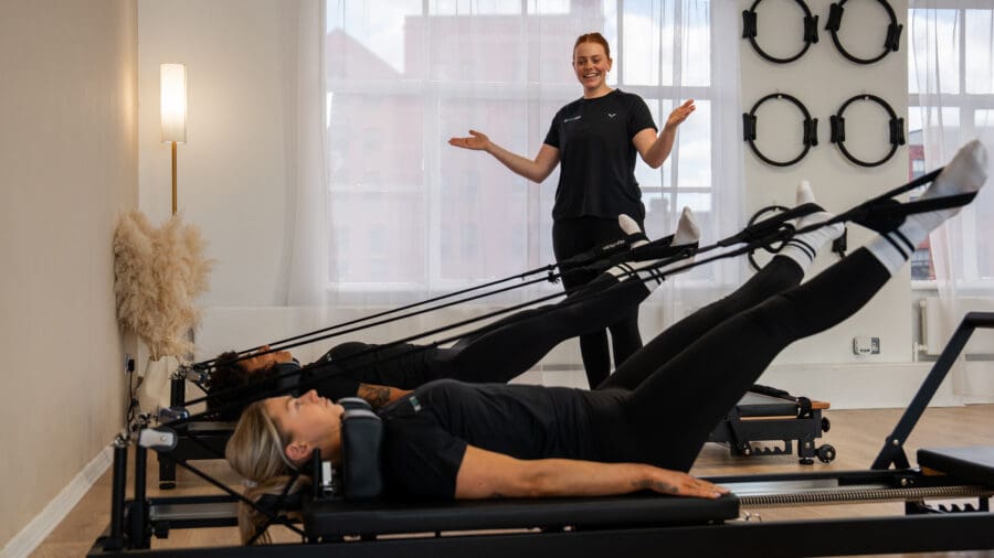 Pilates instructor teaching students how to use a reformer. Pilates instructor teaching students how to use a reformer.