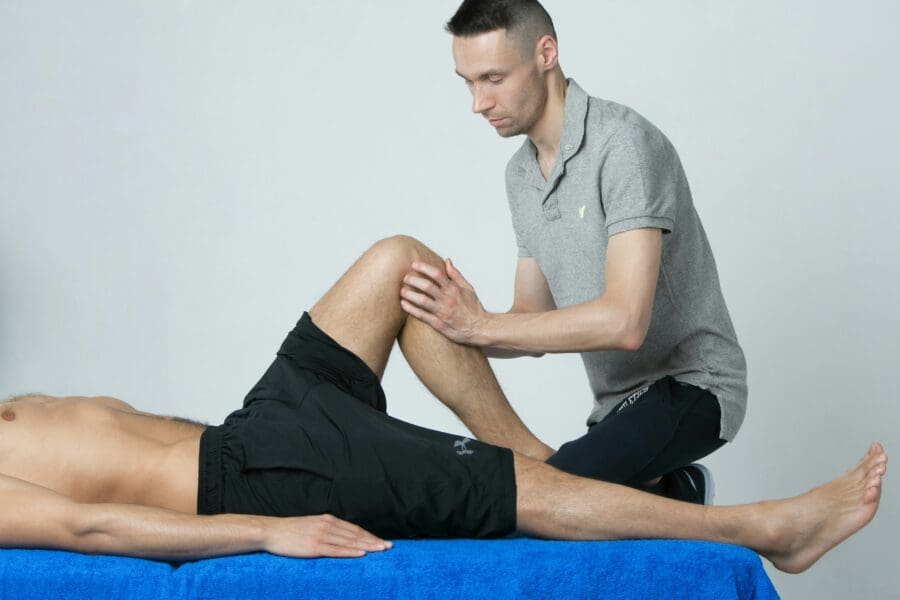 Personal trainer guiding a client through assisted stretching exercises to improve range of motion and flexibility in a gym setting.